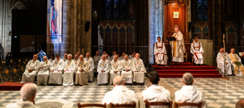Photo de Mgr James prêchant entouré de prêtres du diocèse